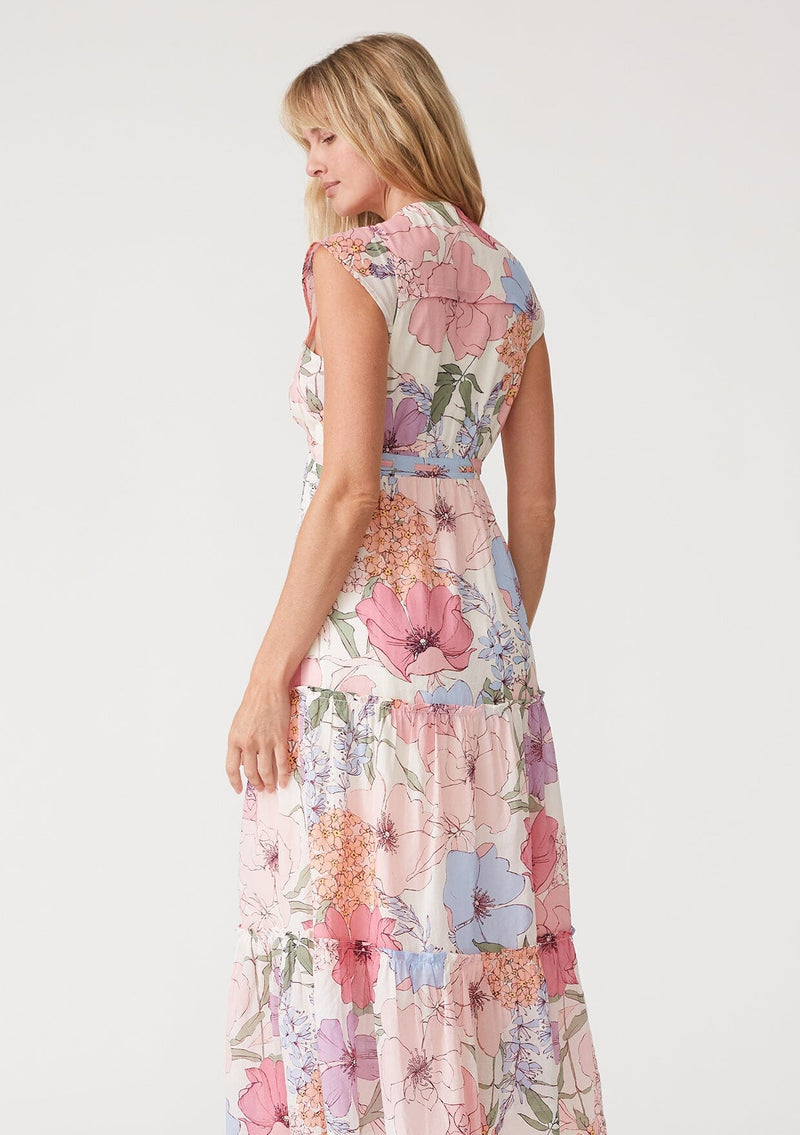 [Color: Ivory/Natural] A close up back facing image of a blonde model wearing a pink floral maxi dress. With short cap sleeves, a v neckline, a button front, an empire waist, a ruffle trimmed tiered skirt, and a drawstring waist with tassel ties. 