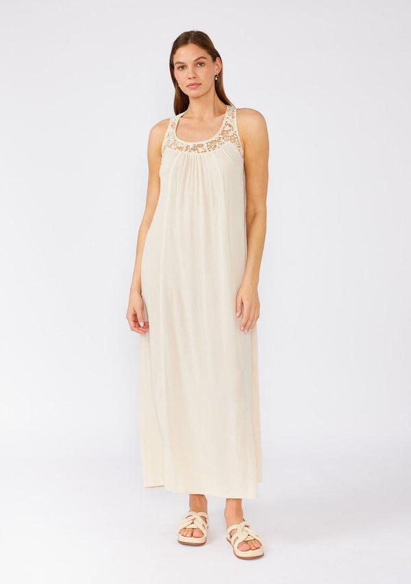 [Color: Natural] A front facing image of a brunette model wearing a flowy sleeveless bohemian maxi dress in ivory. With a crochet top, a scooped neckline, and an open back detail. 