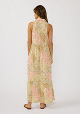 [Color: Dusty Peach/Rust] A back facing image of a brunette model wearing a bohemian sleeveless maxi dress designed in a peach and rust floral print. With a collared neckline, a self covered button front top, a long tiered skirt, and side pockets. 