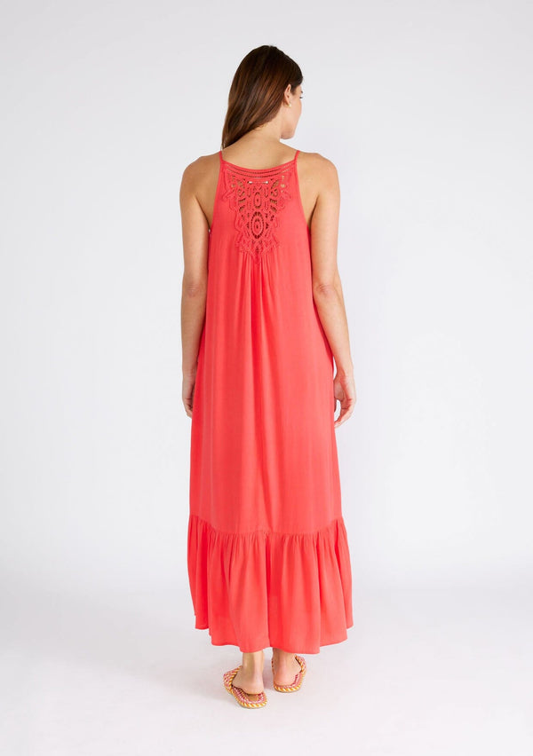 [Color: Hibiscus] A back facing image of a brunette model wearing a red bohemian sleeveless maxi dress. With spaghetti straps, a scoop neckline, side pockets, a long flowy tiered skirt, and a sheer lace racerback detail. 