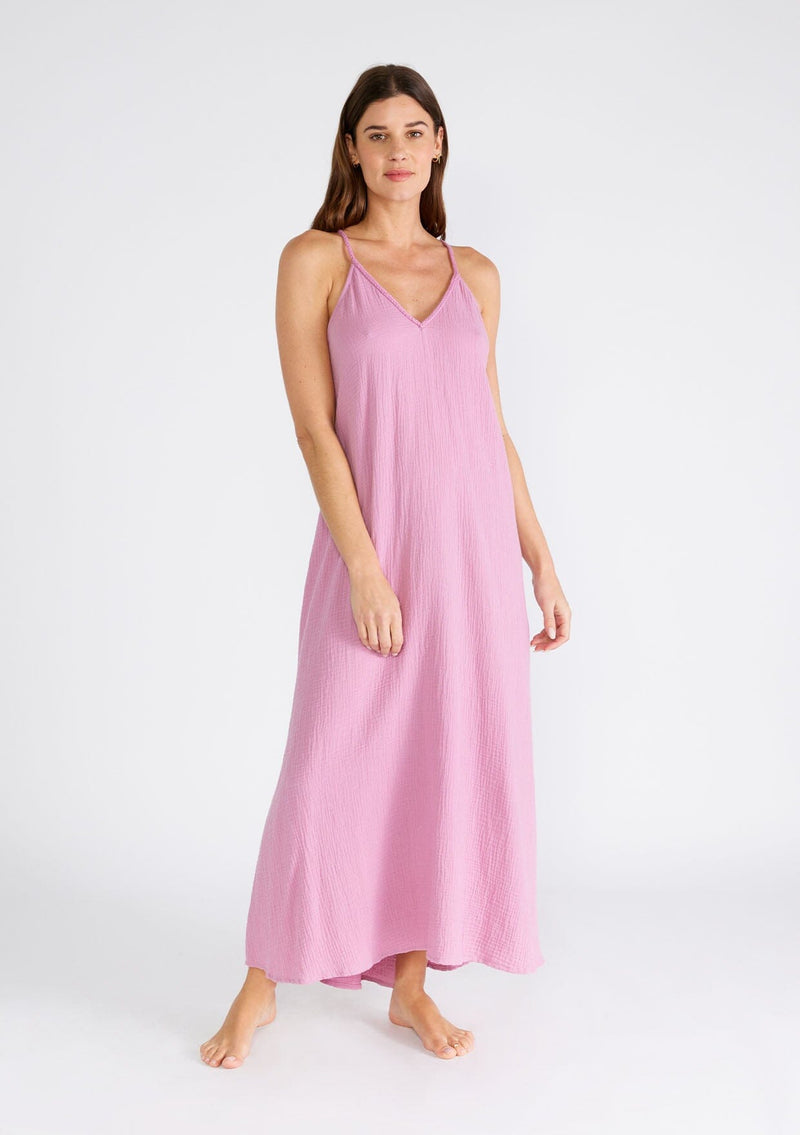 [Color: Orchid] A front facing image of a brunette model wearing a light purple bohemian sleeveless maxi dress crafted from cotton gauze. With braided straps, a v neckline, a relaxed, flowy body, and a sheer crochet mesh racerback detail.