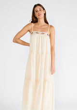 [Color: Light Peach] A close up front facing image of a brunette model wearing a light peach pink sleeveless maxi dress. A lightweight bohemian style with embroidered detail at the neckline, adjustable spaghetti straps, a lace trimmed tiered skirt, a straight neckline, and a long flowy fit. 