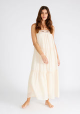 [Color: Light Peach] A front facing image of a brunette model wearing a light peach pink sleeveless maxi dress. A lightweight bohemian style with embroidered detail at the neckline, adjustable spaghetti straps, a lace trimmed tiered skirt, a straight neckline, and a long flowy fit. 
