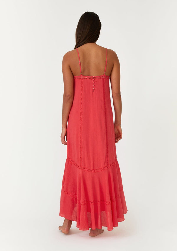 [Color: Hibiscus] A back facing image of a bright red bohemian sleeveless maxi dress. With adjustable spaghetti straps, a v neckline, a flowy tiered skirt with a high low hemline, a loop button up back detail, and lace trim. 