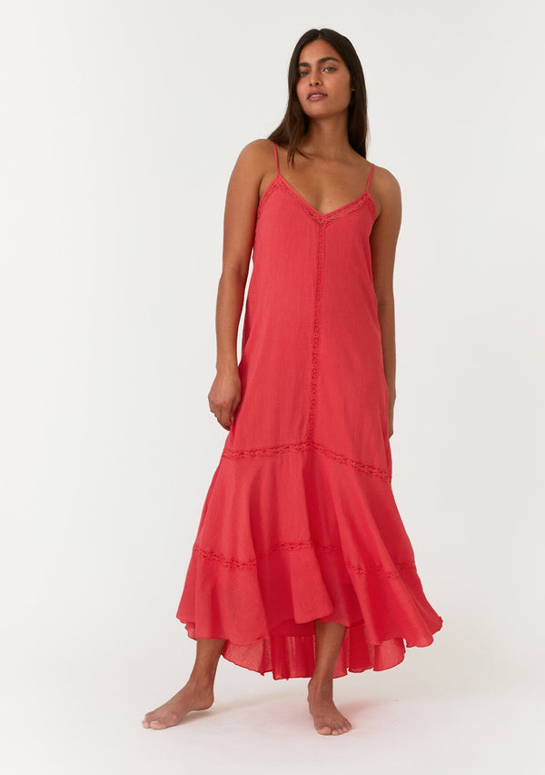 [Color: Hibiscus] A front facing image of a bright red bohemian sleeveless maxi dress. With adjustable spaghetti straps, a v neckline, a flowy tiered skirt with a high low hemline, a loop button up back detail, and lace trim. 