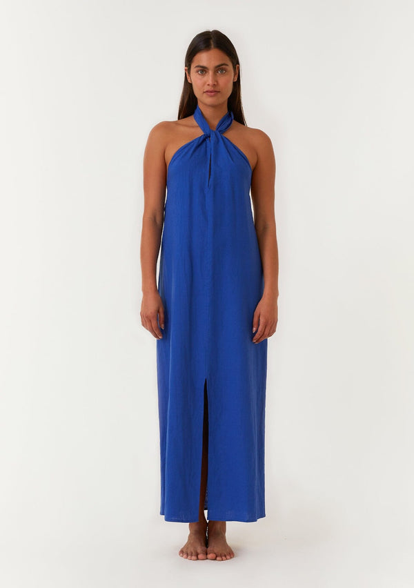 [Color: Cobalt] A front facing image of a brunette model wearing a bright cobalt blue halter maxi dress. With a twist front halter neckline, adjustable tie, front slit, and sexy open back. Perfect for the beach or the pool. 