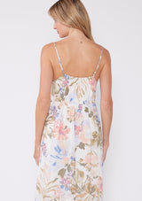 [Color: Off White/Periwinkle] A back facing image of a blonde model wearing a dreamy bohemian mid length sleeveless dress in an off white and periwinkle blue floral print. With adjustable spaghetti straps, a v neckline, a tiered flowy skirt, a button front, and textured clip dot details. 