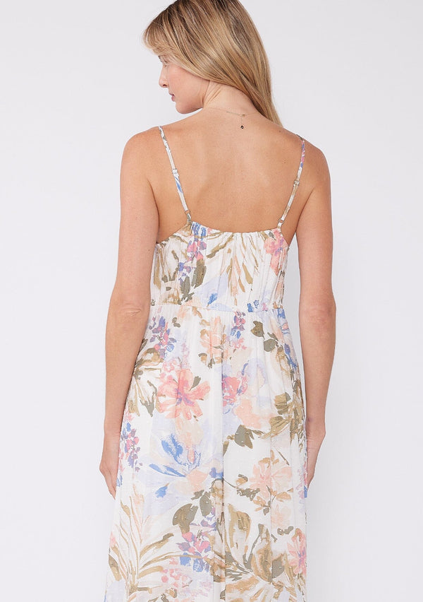 [Color: Off White/Periwinkle] A back facing image of a blonde model wearing a dreamy bohemian mid length sleeveless dress in an off white and periwinkle blue floral print. With adjustable spaghetti straps, a v neckline, a tiered flowy skirt, a button front, and textured clip dot details. 
