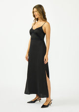 [Color: Black] A side facing image of a brunette model wearing a classic lace trim maxi dress with a v neckline, spaghetti straps, and side slits. 