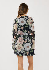 [Color: Black/Blush] A back facing image of a brunette model wearing a black and pink floral mini dress with long bell sleeves, a surplice front, and an elastic waist with side tie detail. A flowy chiffon mini dress for brunch and special occasions. 