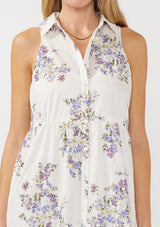 [Color: Off White/Lilac] A detail image of a blonde model wearing a sleeveless purple floral midi shirt dress. The dress features embroidered eyelets, a collared neckline, a button-front design, and a tiered skirt. Ideal for weddings, Easter, or other special occasions.