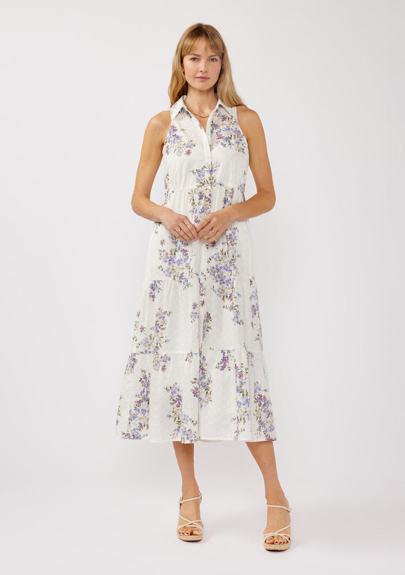 [Color: Off White/Lilac] A front-facing image of a blonde model wearing a sleeveless purple floral midi shirt dress. The dress features embroidered eyelets, a collared neckline, a button-front design, and a tiered skirt. Ideal for weddings, Easter, or other special occasions.