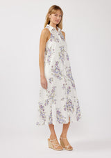 [Color: Off White/Lilac] A side-facing image of a blonde model wearing a sleeveless purple floral midi shirt dress. The dress features embroidered eyelets, a collared neckline, a button-front design, and a tiered skirt. Ideal for weddings, Easter, or other special occasions.
