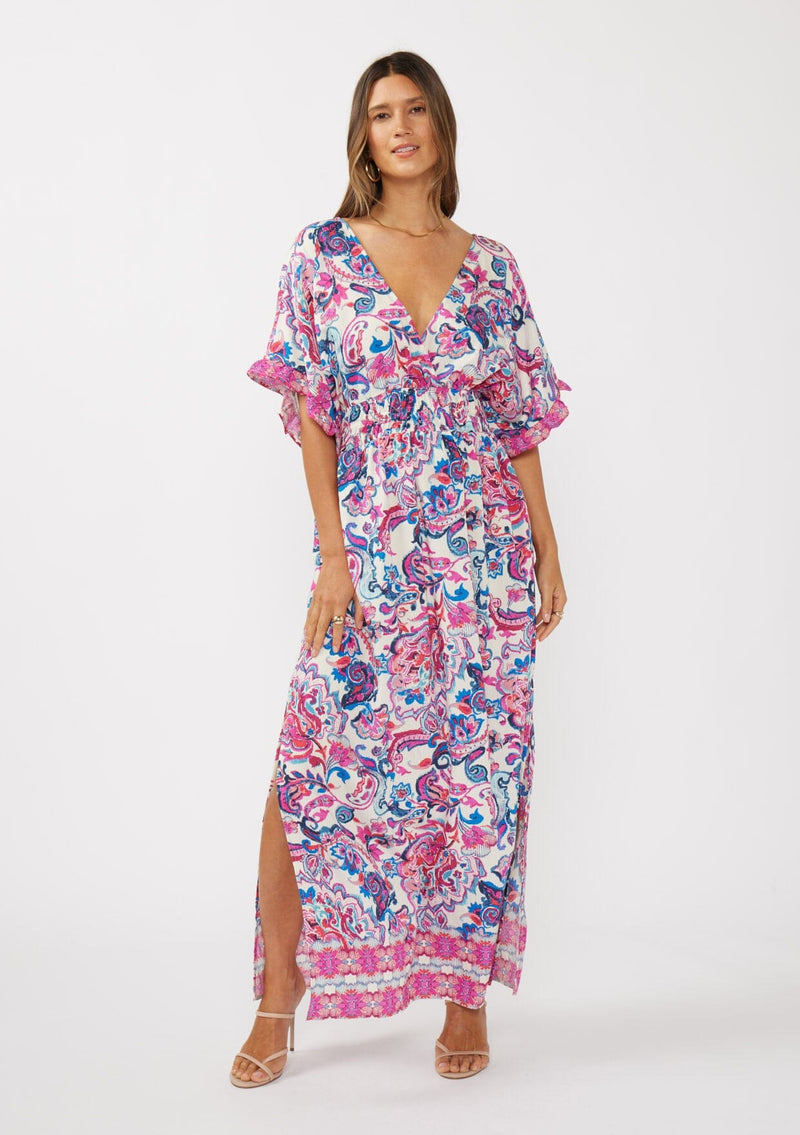 [Color: Natural/Dusty Pink] A front facing image of a brunette model wearing a pink and blue floral print kimono sleeve maxi dress with a ruffle trim, smocked waist, double v-neckline, and side slits. Perfect for spring special occasions. 