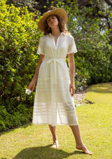 [Color: White] A front facing image of a blonde model in a white cotton midi dress featuring a collared neckline, button front, self-tie waist belt, lace trim, and pintuck details. A timeless boho spring style.