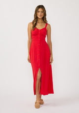 [Color: Tomato] A front facing image of a brunette model wearing a classic red maxi dress. This linen blend maxi features a button front, side pockets, and a smocked back.