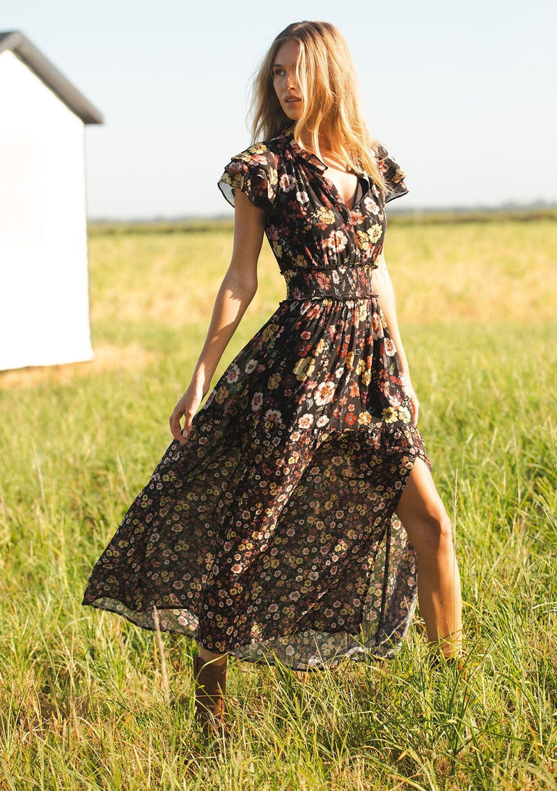 [Color: Black/Rust] A front facing image of a black floral maxi dress with short flutter sleeves, a split v-neckline, a smocked waist, and side slit. Adorned with ruffle trims, this romantic fall maxi dress is perfect for weddings, holidays, and other special occasions. 