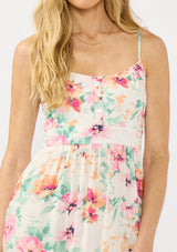[Color: Ivory/Fuchsia] A detail image of a blonde model wearing a spring floral midi dress with adjustable spaghetti straps, quilted bodice, and side pockets.