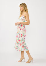 [Color: Ivory/Fuchsia] A side facing image of a blonde model wearing a spring floral midi dress with adjustable spaghetti straps, quilted bodice, and side pockets.