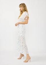 [Color: White/Blue] A side facing image of a blonde model wearing a spring white and blue floral maxi dress with short dolman sleeves, tassel ties, a v neckline, and a smocked waist. 