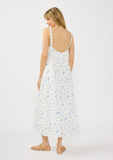 [Color: White/Blue] A back facing image of a blonde model wearing a white and blue floral maxi dress with a relaxed fit, scoop neckline, elastic shoulder straps, and  side pockets.