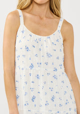 [Color: White/Blue] A detail image of a blonde model wearing a white and blue floral maxi dress with a relaxed fit, scoop neckline, elastic shoulder straps, and  side pockets.