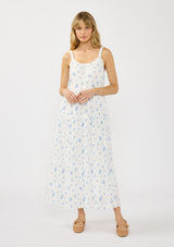 [Color: White/Blue] A front facing image of a blonde model wearing a white and blue floral maxi dress with a relaxed fit, scoop neckline, elastic shoulder straps, and  side pockets.