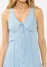 [Color: Light Wash] A detail image of a blonde model wearing a denim midi dress with a v neckline and button front. 