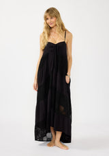 [Color: Black] A front facing image of a blonde model wearing a black bohemian maxi dress with a patchwork lace, sweetheart neckline, tie front detail, and a flowy tiered silhouette. 