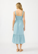 [Color: Aqua Blue] A back facing image of a blonde model wearing a light blue midi dress with a smocked bust, button front, and ruffle tiered  hemline. 