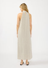 [Color Natural/Black] A back facing image of a blonde model wearing a striped halter maxi dress with a crossover neckline, single pleat, and side pockets.