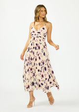 [Color: Peach/Plum] A front facing image of a brunette model wearing a pink and purple floral maxi dress with a pleated design, v neckline, spaghetti straps, and a cross back with tie back detail. 