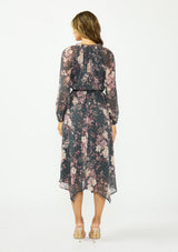 [Color: Grey/Dusty Rose] A back facing image of a brunette model wearing a grey floral handkerchief dress with clipped lurex, a surplice v neckline, long sleeves, and an elastic waist. 