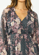 [Color: Grey/Dusty Rose] A detail image of a brunette model wearing a grey floral handkerchief dress with clipped lurex, a surplice v neckline, long sleeves, and an elastic waist. 