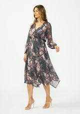 [Color: Grey/Dusty Rose] A side facing image of a brunette model wearing a grey floral handkerchief dress with clipped lurex, a surplice v neckline, long sleeves, and an elastic waist. 
