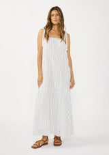 [Color: White/Denim Blue] A front facing image of a brunette model wearing a white and blue striped maxi dress with a shirred texture, square neckline, and tie shoulders. 