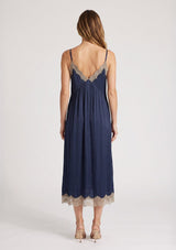[Color: Navy/Taupe] A back facing image of a blonde model wearing a lace midi dress with spaghetti straps and an empire waist. 