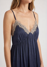 [Color: Navy/Taupe] A detail image of a blonde model wearing a lace midi dress with spaghetti straps and an empire waist. 