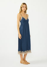 [Color: Navy/Taupe] A side facing image of a blonde model wearing a navy blue lace midi dress with spaghetti straps and an empire waist. 