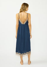 [Color: Navy/Taupe] A back facing image of a blonde model wearing a navy blue lace midi dress with spaghetti straps and an empire waist. 