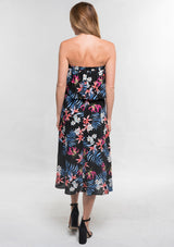 [Color: Black/Coral] A back facing image of a woman modeling a strapless top and matching midi skirt set with a black and blue tropical floral print paired with black block heels.