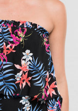 [Color: Black/Coral] A detail image of a woman modeling a strapless top and matching midi skirt set with a black and blue tropical floral print paired with beige strappy high-heeled sandals.