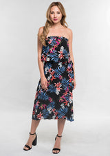 [Color: Black/Coral] A front facing image of a woman modeling a strapless top and matching midi skirt set with a black and blue tropical floral print paired with black block heels.