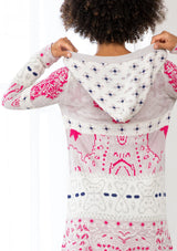 [Color: Orchid/Raspberry] A back facing image of a brunette model wearing a vibrant boho patterned knit cardigan with long cozy sleeves, open front, and hoodie. An effortless statement sweater for easy layering.  