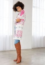 [Color: Orchid/Raspberry] A side facing image of a brunette model wearing a vibrant boho patterned knit cardigan with long cozy sleeves, open front, and hoodie. An effortless statement sweater for easy layering.  