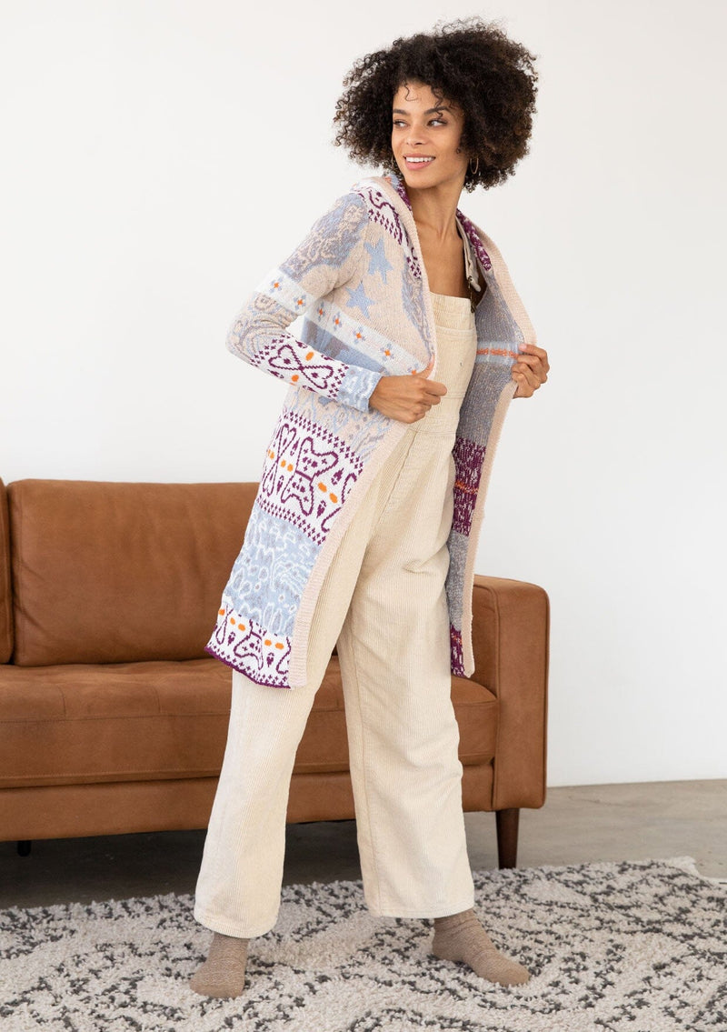 [Color: Sky/Plum] A front facing image of a brunette model wearing a vibrant boho patterned knit cardigan with long cozy sleeves, open front, and hoodie. An effortless statement sweater for easy layering.  