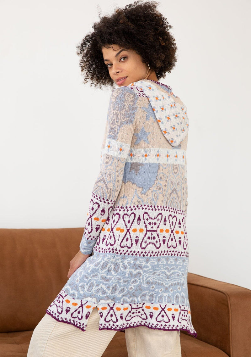 [Color: Sky/Plum] A side facing image of a brunette model wearing a vibrant boho patterned knit cardigan with long cozy sleeves, open front, and hoodie. An effortless statement sweater for easy layering.  