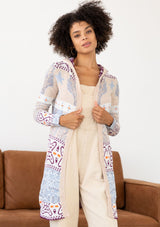 [Color: Sky/Plum] A front facing image of a brunette model wearing a vibrant boho patterned knit cardigan with long cozy sleeves, open front, and hoodie. An effortless statement sweater for easy layering.  
