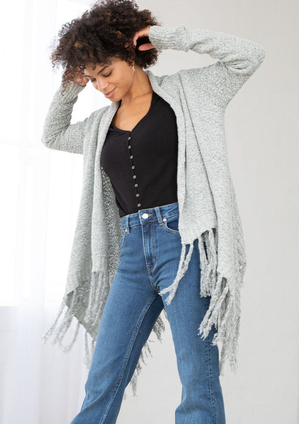 [Color: Grey/Ivory] A front facing image of a marled knit cardigan with a shawl waterfall collar with a fringe hem. A boho chic cardigan for the fall season. 