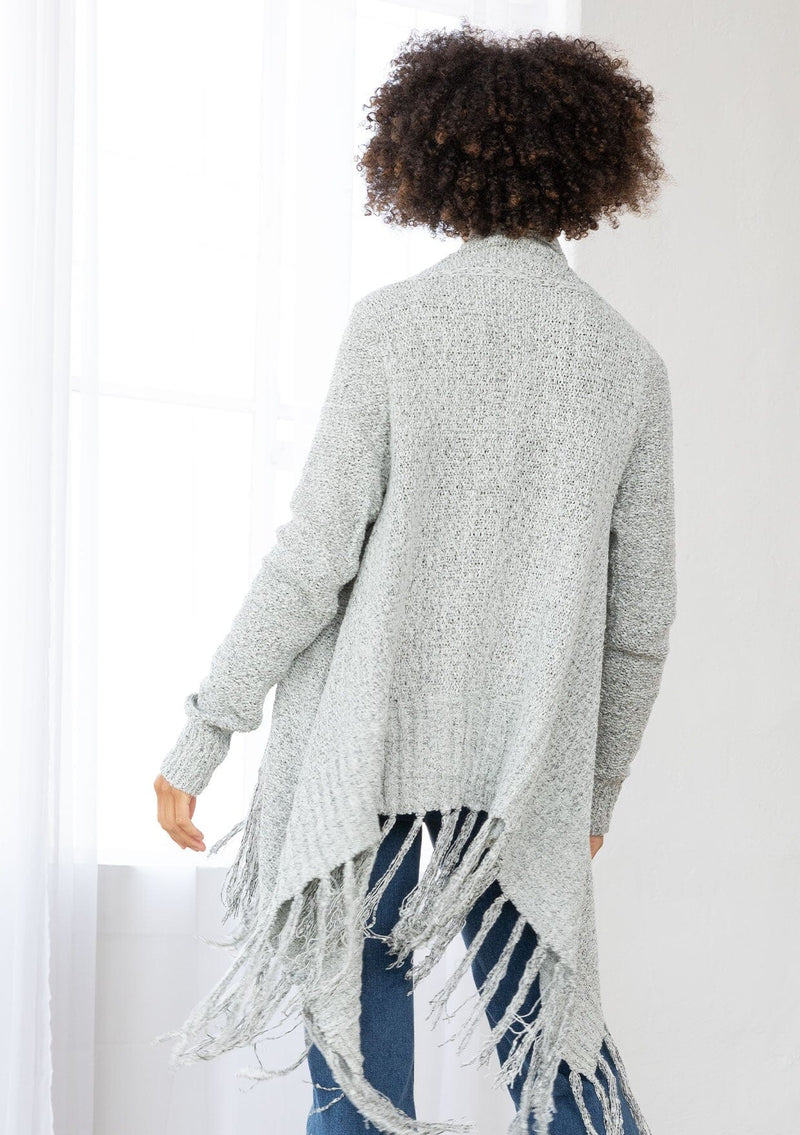[Color: Grey/Ivory] A back facing image of a marled knit cardigan with a shawl waterfall collar with a fringe hem. A boho chic cardigan for the fall season. 